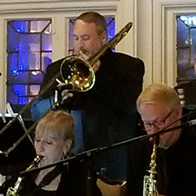 Medium close-up of a jazz band performing with a trombonist and saxophonists