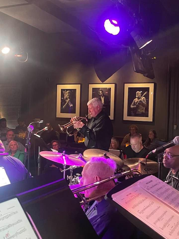 A JoySwing trumpeter performing in a purple-lit jazz club