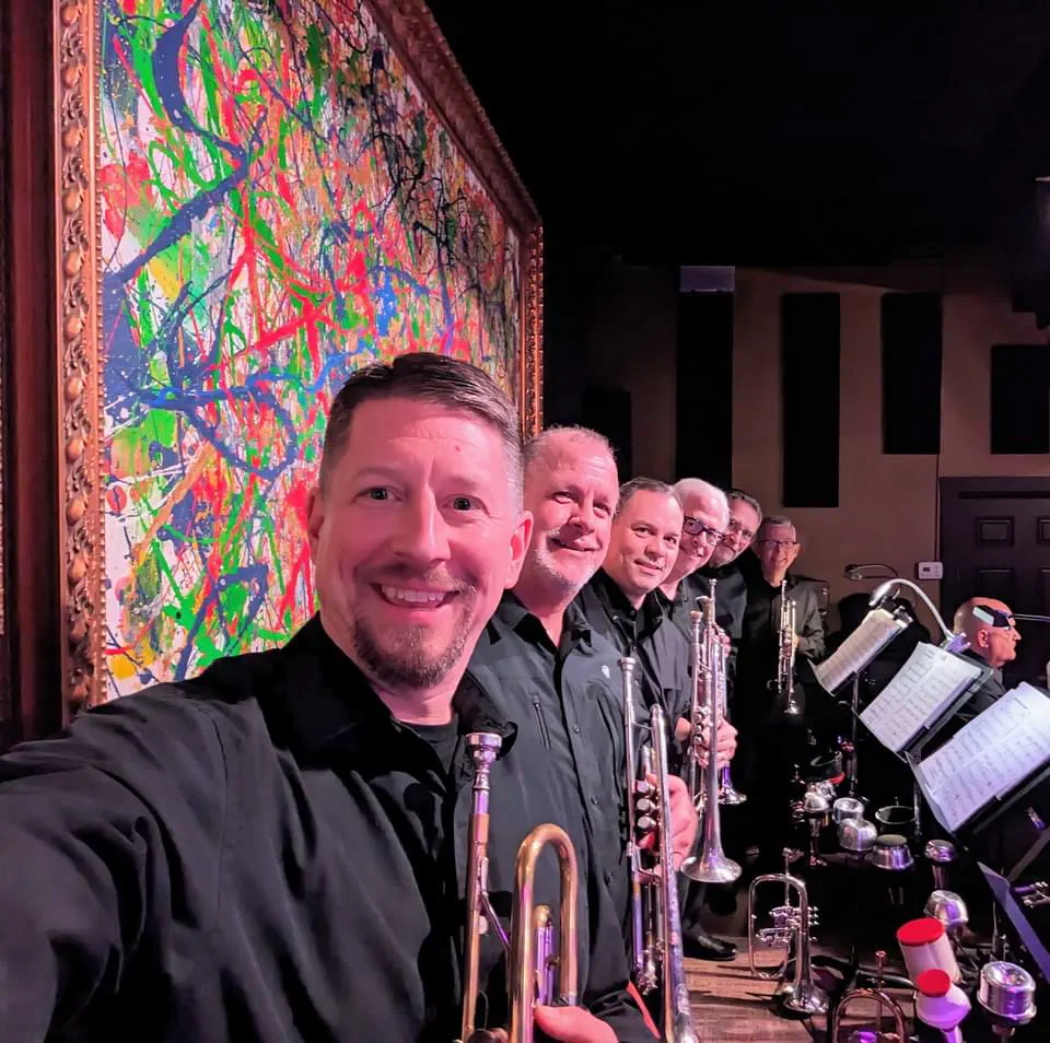 JoySwing musicians with saxophones and brass instruments beside the stage