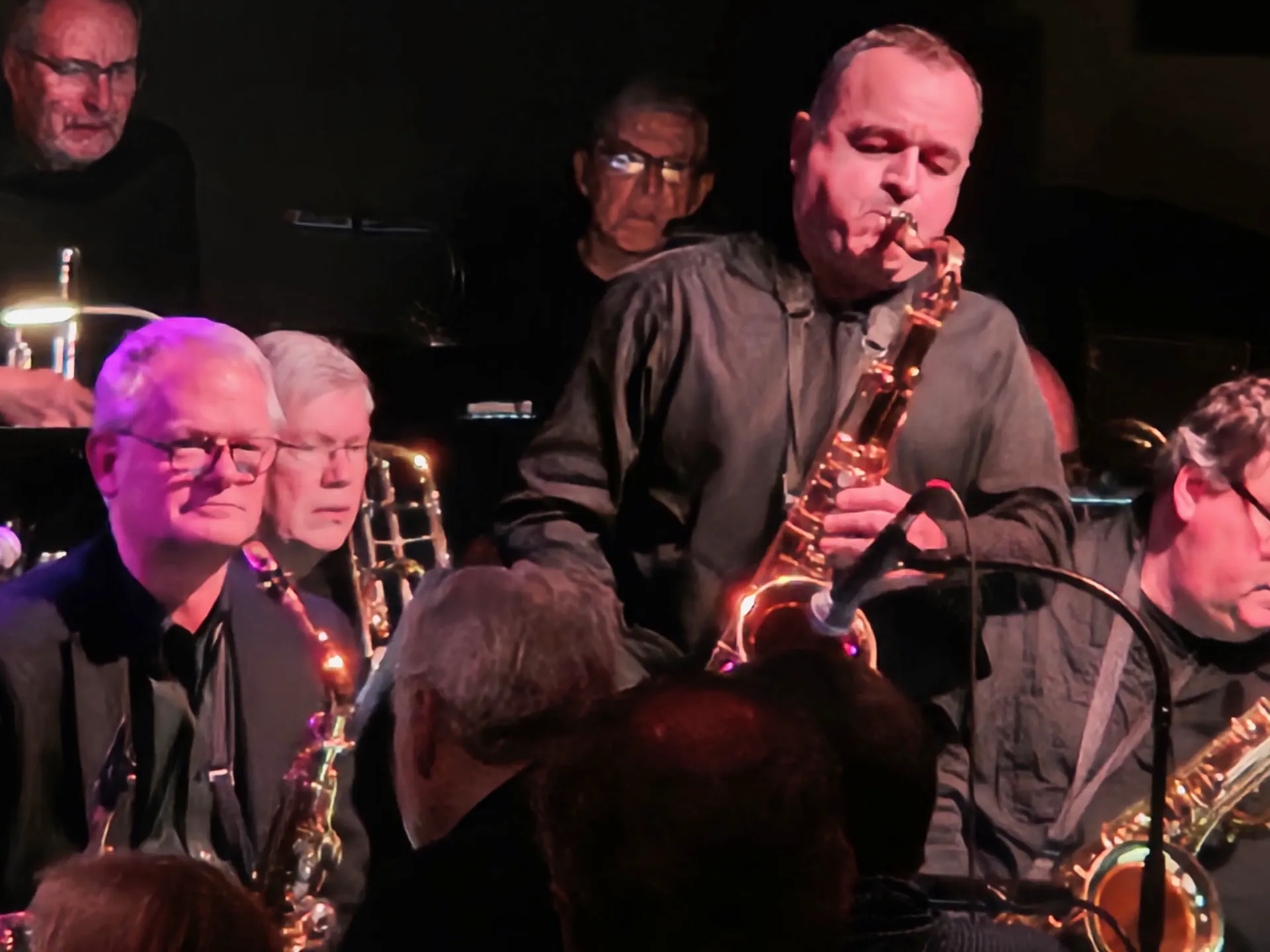 JoySwing saxophone section performing under purple stage lights